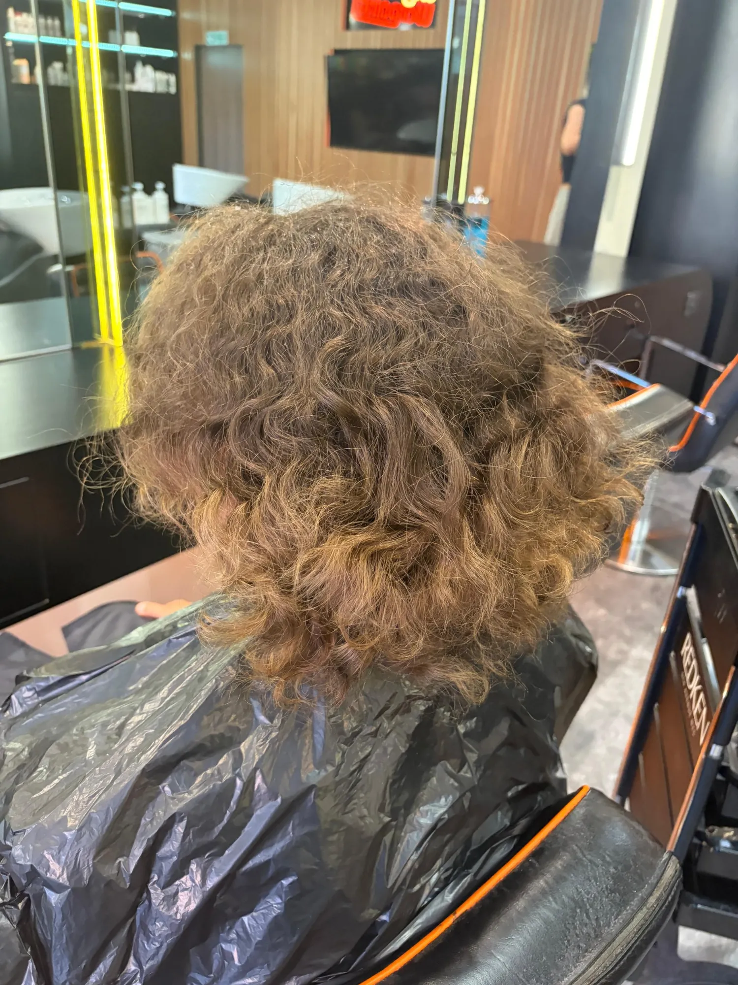 Back view of the client’s shorter natural curls before curly extensions with Claire.