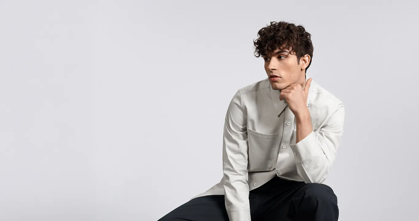Goldwell Texture Dimensions campaign model with a short curly perm, photographed against a pale background.